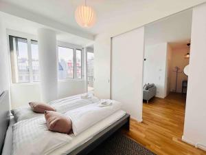 een witte slaapkamer met een bed met kussens erop bij Designer flat to feel good in in Wenen