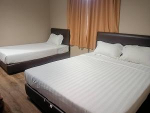 a bedroom with two beds and a window at M BOUTIQUE INN (PERMYJAYA) in Miri