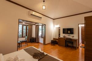 a bedroom with a bed and a desk and a television at Scarlet Resort in Matheran