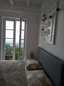 a bedroom with a bed and a large window at Appartement Magliolo Ligurie / Piscine - SPA - Vue in Magliolo