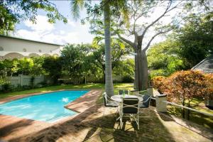 a patio with a table and chairs next to a swimming pool at A wonderful 5 bedroomed 4 bathroom Villa with swimming pool gym garden of the highest quality - 2215 in Victoria Falls