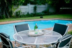 a table with a bottle on it next to a pool at A wonderful 5 bedroomed 4 bathroom Villa with swimming pool gym garden of the highest quality - 2215 in Victoria Falls