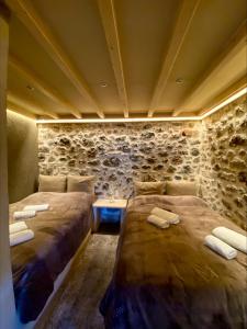 two beds in a room with a stone wall at D&P Cell Oneiro. in Kalavrita