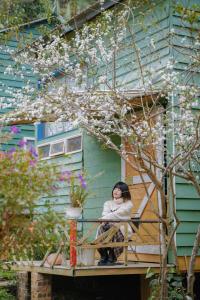una mujer sentada en un balcón de una casa en Stella Mộc Châu Homestay, en Mộc Châu