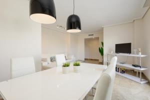 een witte eetkamer met een witte tafel en stoelen bij Moderno apartamento de dos dormitorios al lado del Golf in Estepona