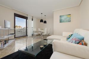 een woonkamer met een witte bank en een glazen tafel bij Moderno apartamento de dos dormitorios al lado del Golf in Estepona