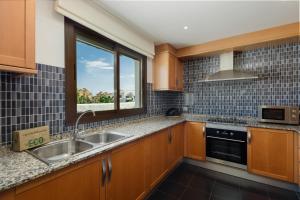 een keuken met houten kasten, een wastafel en een raam bij Moderno apartamento de dos dormitorios al lado del Golf in Estepona