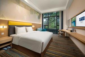 Cette chambre comprend un lit et une télévision à écran plat. dans l'établissement Holiday Inn Express Emei Mountain, an IHG Hotel, à Emei Shan