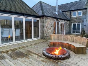 a fire pit on a deck with a house at Winnie Cottage - Hot Tub, Games Room, Sauna, Large Garden in Stocksfield