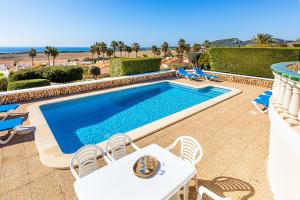 uma piscina com mesa e cadeiras e a praia em Villa Terra em Son Bou