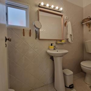 La salle de bains est pourvue d'un lavabo, de toilettes et d'un miroir. dans l'établissement Bea's Bed & Breakfast, à Tavira
