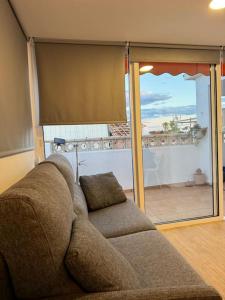 een bank in de woonkamer met uitzicht op een patio bij Playa Villajoyosa, apartamento in Villajoyosa