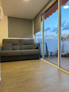 een woonkamer met een bank en een balkon bij Playa Villajoyosa, apartamento in Villajoyosa