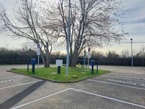 un estacionamiento con parquímetros azules y un árbol en Hotel Le Saint Vincent Lyon Sud, en Vourles