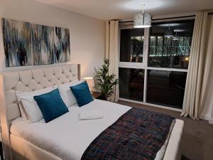 a bedroom with a bed with blue pillows and a window at Luxury Dockview 3 Beds Excel London in London
