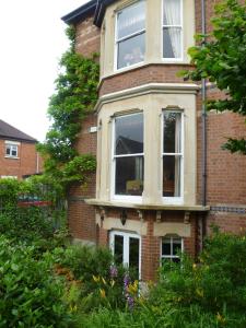 una casa de ladrillo con dos ventanas y arbustos en Laurel House, en Cheltenham