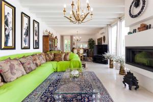 een woonkamer met een groene bank en een kroonluchter bij B&B RED WINE COUNTRY HOUSE in Castel San Pietro Terme