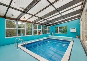 a swimming pool with blue walls and windows at Boslandew House in Paul