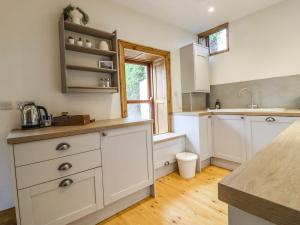a kitchen with white cabinets and a sink at Chews Cottage in Pateley Bridge