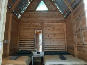 two beds in a wooden room with a window at Nature Glamping in Matheran