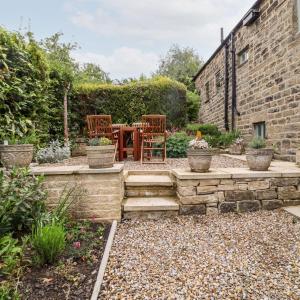 a patio with chairs and a table in a garden at Chews Cottage in Pateley Bridge