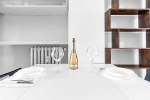 a white table with two glasses and a bottle of wine at -Ethnic Design Loft- con soppalco [Città Studi M2] in Milan