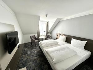 a bedroom with a white bed and a tv at Lindgart Hotel Minden in Minden