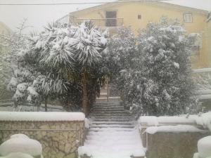 a snow covered yard with stairs and a house at Appartamento 3 letti con cucina e parcheggio privato gratuito in Candela