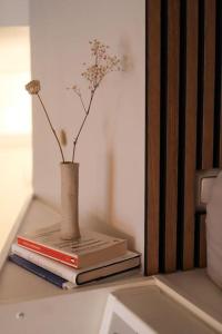 two books and a vase with flowers on a shelf at Cozy and stylish studio in Kamppi in Helsinki