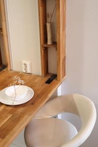 two white chairs sitting at a wooden table with a plate at Cozy and stylish studio in Kamppi in Helsinki