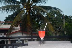 a drink sitting on a table with a palm tree in the background at The Kings Villa. in Wattala