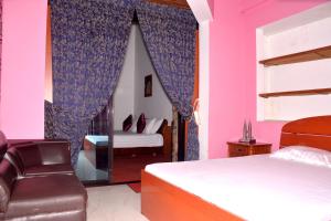 a bedroom with a bed and a chair and a mirror at The Kings Villa. in Wattala