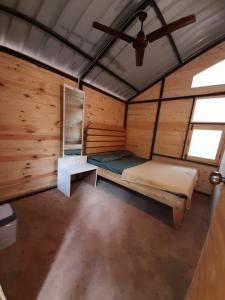 a bedroom in a log cabin with a bed and a table at Nature Glamping in Matheran