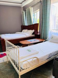 a bedroom with two beds and tables and a window at OLENG'OTI GARDENS in Narok