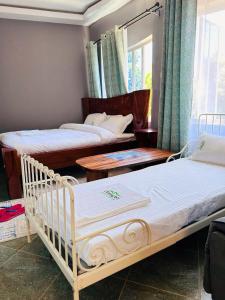 sypialnia z 2 łóżkami i stolikami oraz oknem w obiekcie OLENG'OTI GARDENS w mieście Narok