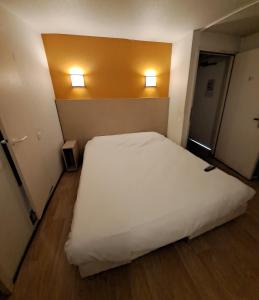 una camera con un letto bianco e due luci sul muro di Hotel HECO Lyon sud Vienne a Vienne