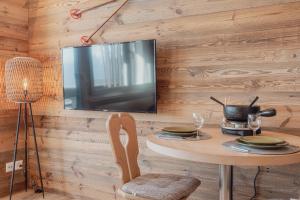 d'une salle à manger avec une table et une télévision murale. dans l'établissement Charmant studio avec une vue imprenable, à Nendaz