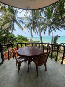 a table and chairs on a balcony with the ocean at WASANA beach hotel in Induruwa