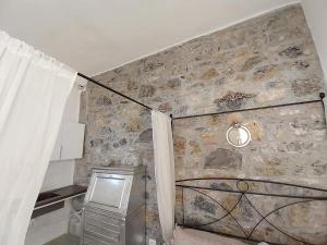 Pokój z kamienną ścianą z oknem i zasłoną w obiekcie Monolocale con bagno, angolo cottura e letto matrimoniale a Baldacchino w mieście Monterotondo +37 zdjęć