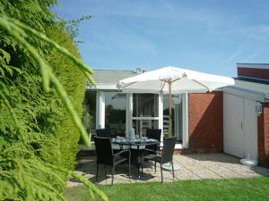 a table and chairs under an umbrella on a patio at Ferienhaus Treibholz in Neuharlingersiel