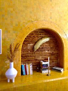 a brick fireplace with aumedumed feather on a shelf with books at Riad Lauriers Blancs in Marrakesh