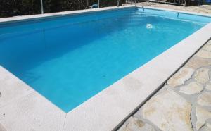 a swimming pool with blue water in a backyard at Apartment Rural Podastrana in Sinj