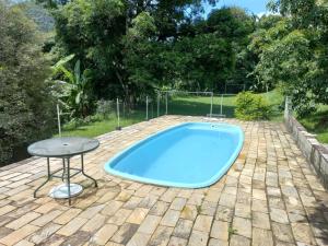 uma piscina com uma mesa num quintal em Sítio das Pedras em Matias Barbosa