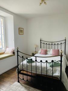 a bedroom with a black bed with pink pillows at Ancien Relais de Poste The Old Post Office in Saint-Martial-dʼAlbarède