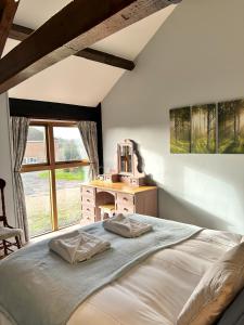 a bedroom with a bed and a desk and a window at The Old Barn - Bramble Farm Cottages in Ferndown