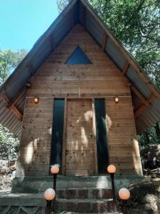 a small wooden building with windows and lights on it at Nature Glamping in Matheran