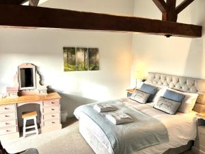 a bedroom with a bed with a tv and a dresser at The Old Barn - Bramble Farm Cottages in Ferndown