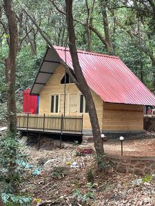 a small cabin in the woods with a red roof at Nature Glamping in Matheran