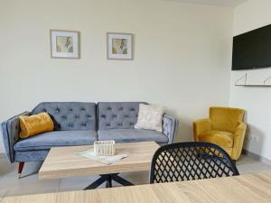 uma sala de estar com um sofá azul e uma mesa em Le Gîte de la Forêt - Montmacq em Thourotte