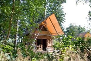 ein Baumhaus mit einem orangenen Dach im Wald in der Unterkunft Village Huttopia Senonches - Perche in Senonches